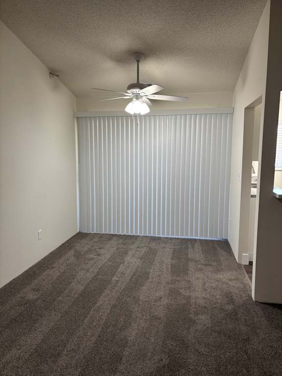 A dining room with a ceiling fan and carpeted floor at Muirfield Apartments.