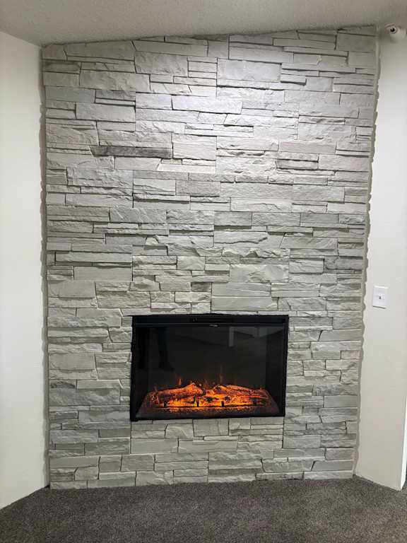 A stone fireplace with a fire burning inside Muirfield Apartments.