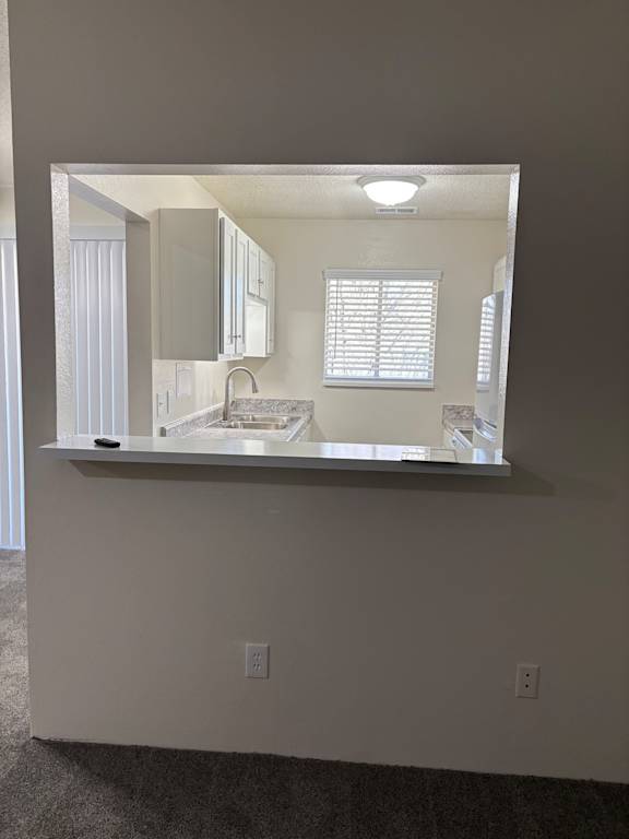 Kitchen with pass-through window and bar seating at Muirfield Apartments.