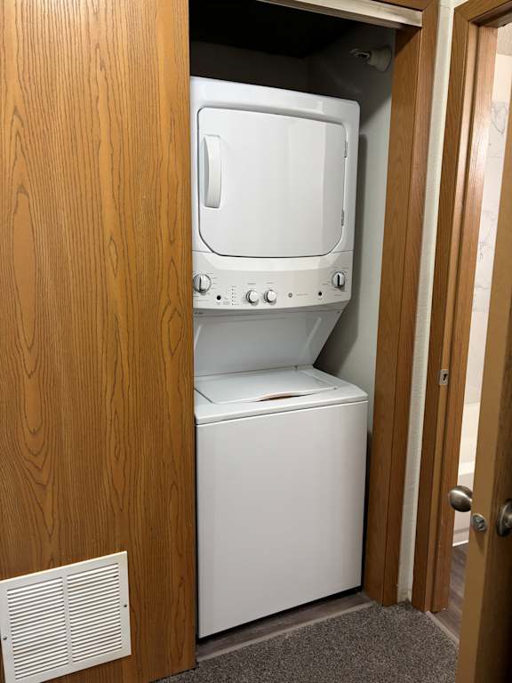 A washer ft. electric dryer combo in white inside laundry cabinet at Muirfield Apartments.