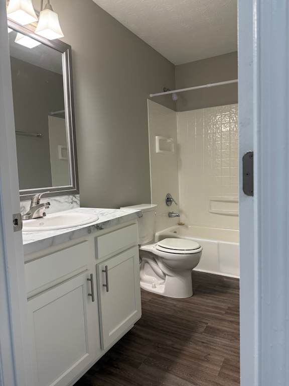A white toilet is in a bathroom with a white sink and a mirror.