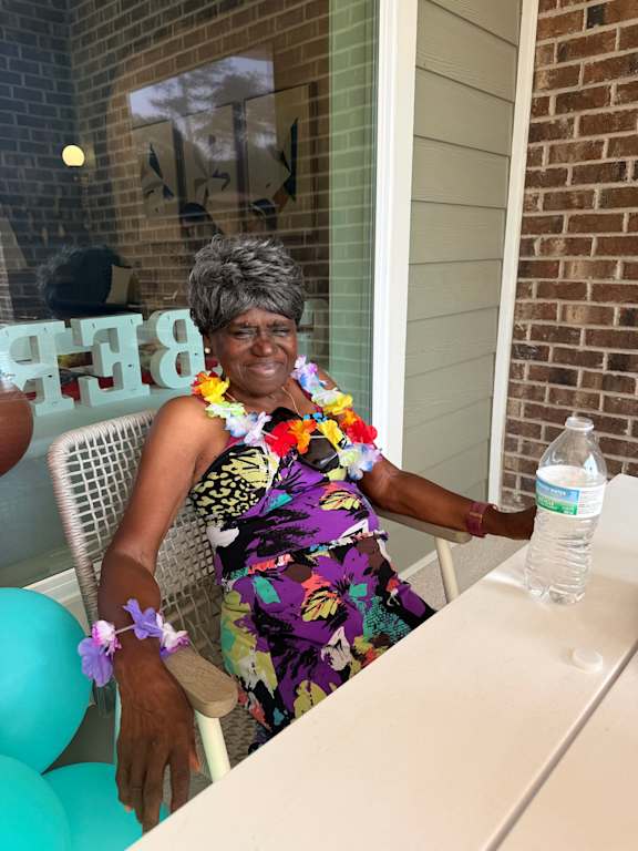 A woman in a floral dress is pouring water from a bottle.