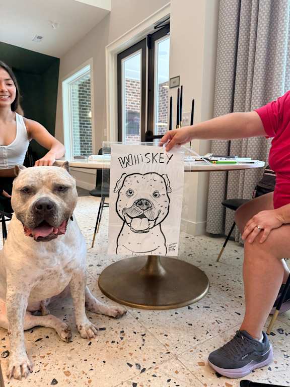 A dog is sitting on a speckled floor next to a woman.