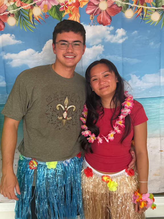 A man and a woman are posing for a picture with a floral backdrop.