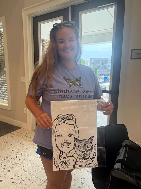 A woman holding a drawing of a boy with glasses.