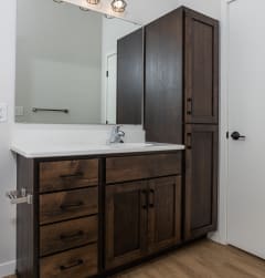 A bathroom with dark wood cabinets and a white sink at Mercantile on Broadway, Fargo, North Dakota 58102