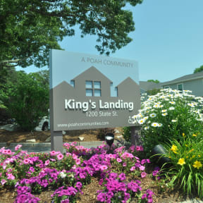 the sign for kings landing in front of a garden of flowers
