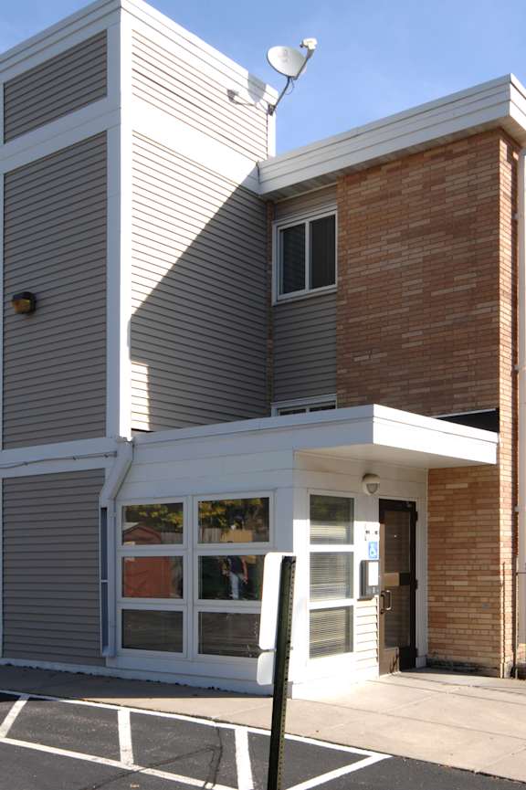 A grey and brown building with a white entrance.