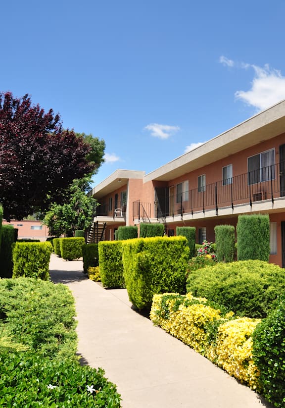 A pathway leads through a well-manicured garden in front of a building.