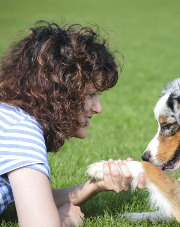 a woman laying on the grass playing with her dog