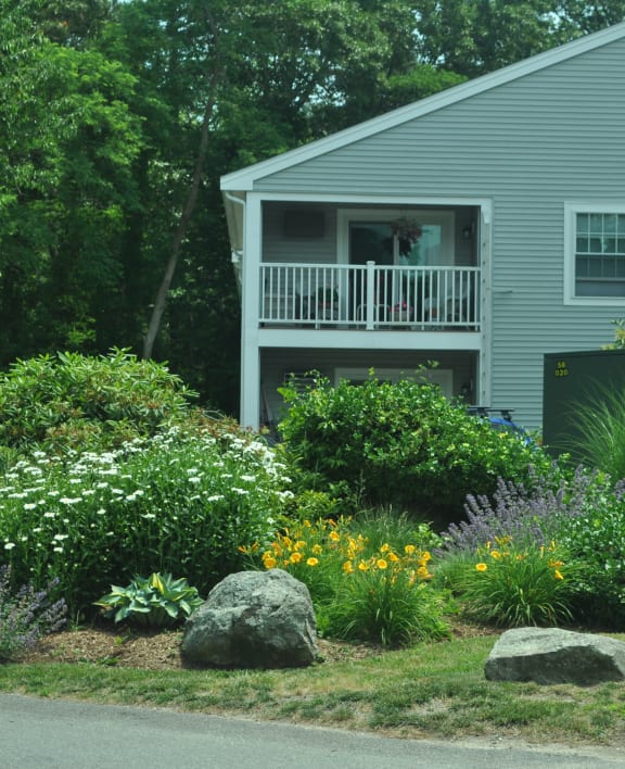 a garden in front of a house with a porch