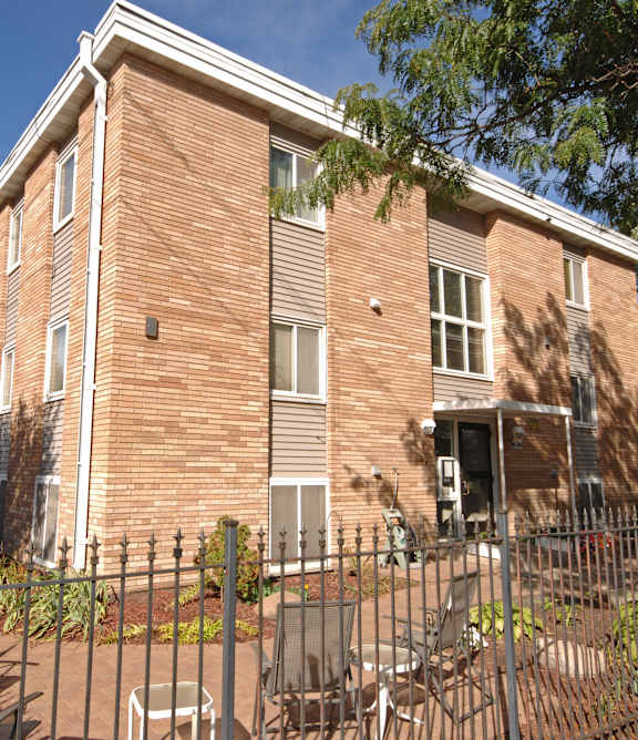 A red brick building with a black fence in front.
