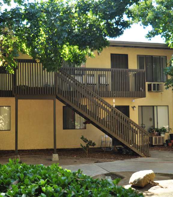 A yellow building with a balcony and a staircase.