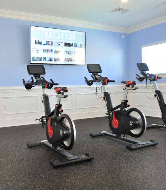 Three stationary bikes are lined up in a room.