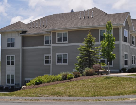 a large gray house with a bench in front of it