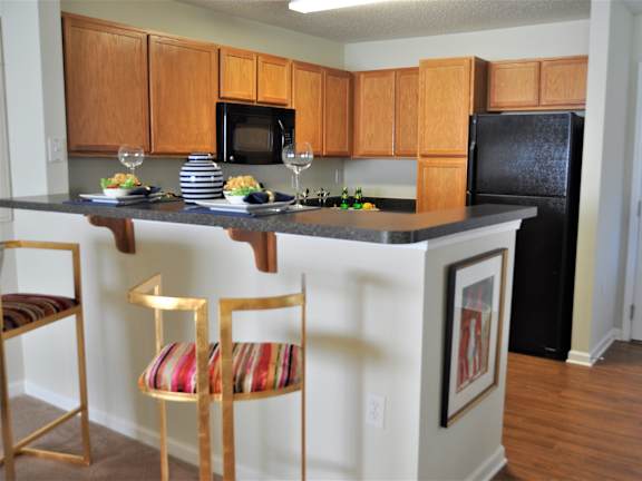 A kitchen with a black refrigerator and wooden cabinets.