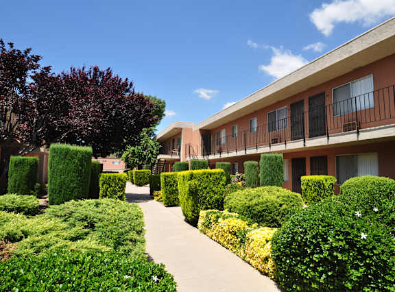 A pathway leads through a well-manicured garden in front of a building.