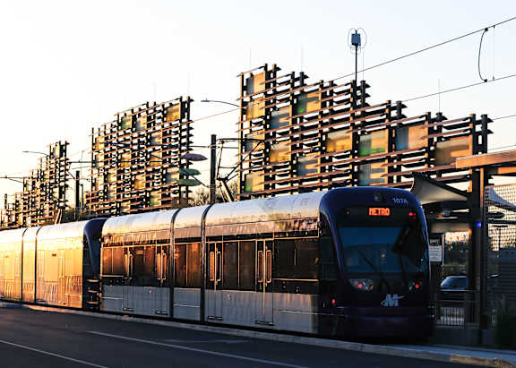 A train is on the tracks with a large structure in the background.