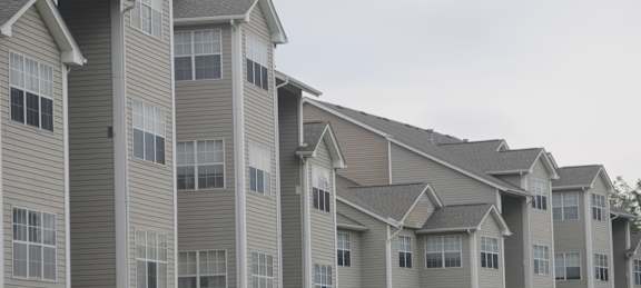 Apartment building with grey siding and white trim.