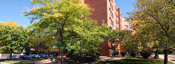 A large red brick building with a tower and trees in front.