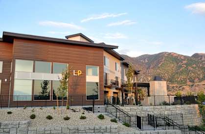 A modern house with a wooden exterior and a stone wall in front.