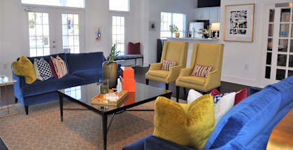 A living room with a blue couch and yellow chairs.