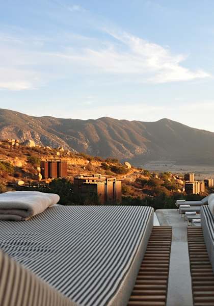 A mountain range is in the background of a building with a striped roof.