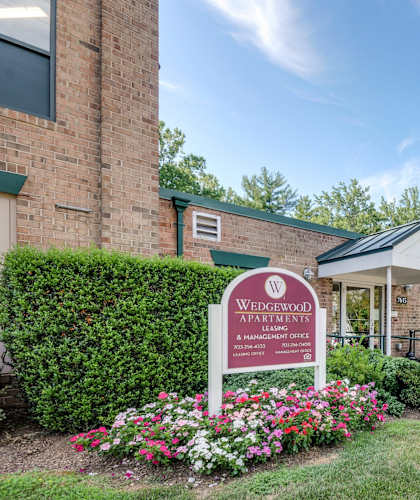 A sign for Wedgewood Apartments is in front of a brick building.