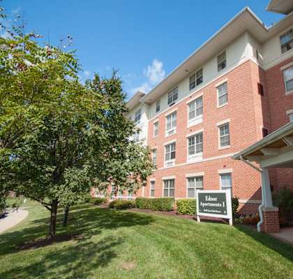 a brick apartment building with a green lawn and a sign
