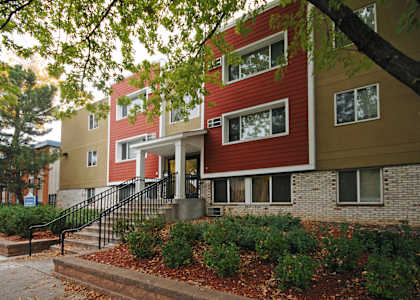 A red and beige building with a black railing on the steps.