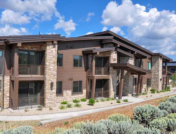 A modern house with a brown exterior and stone pillars.