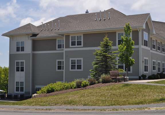 a large gray house with a bench in front of it