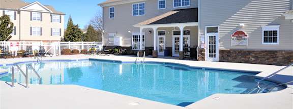 A swimming pool in front of a building with a red and white sign.