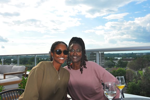 two women sitting at a table on a balcony with wine glasses