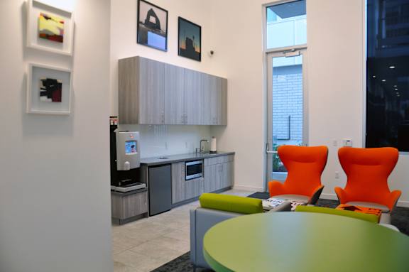 A modern kitchen with orange chairs and a green table. at Liberty Square Apartments - Saltlake City, UT Apartments, Saltlake City, Utah