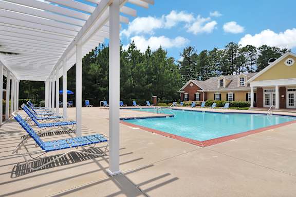 A pool with blue chairs and a white canopy.