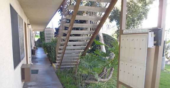 the side of a building with a staircase and a sidewalk