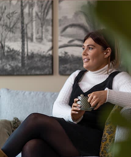 a woman sitting on a couch holding a cup