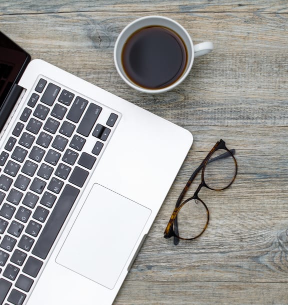 Laptop on table with glasses and cup of coffee at Rolling Hills Apartments, Oregon