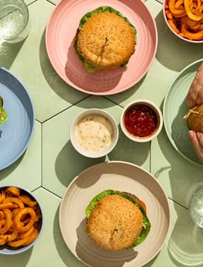 a table topped with plates of food with burgers and dips