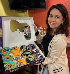 a woman is holding a box of doughnuts