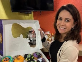 a woman is holding a box of doughnuts