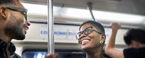 A man and a woman are riding a subway train.
