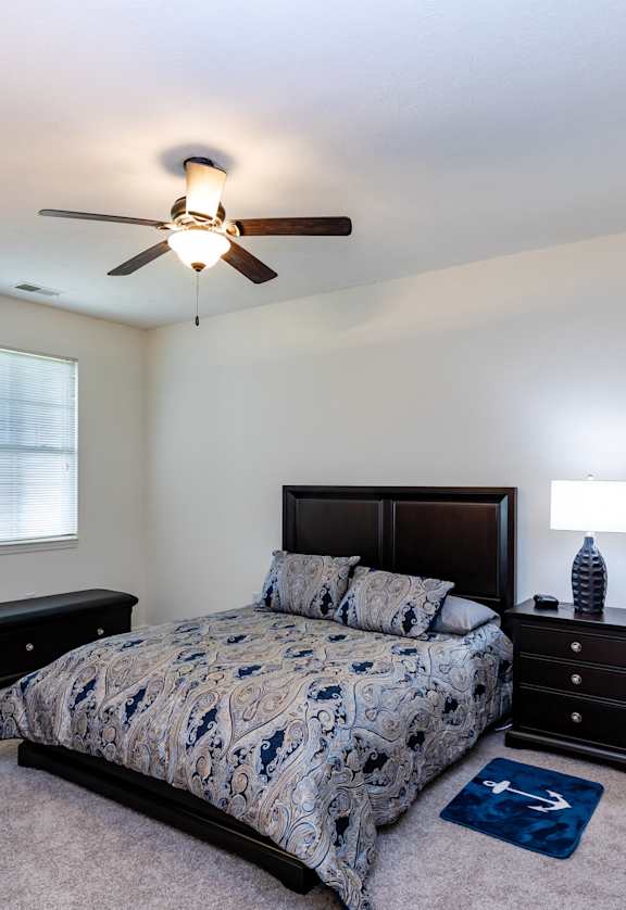 a bedroom with a bed and dressers and a ceiling fan