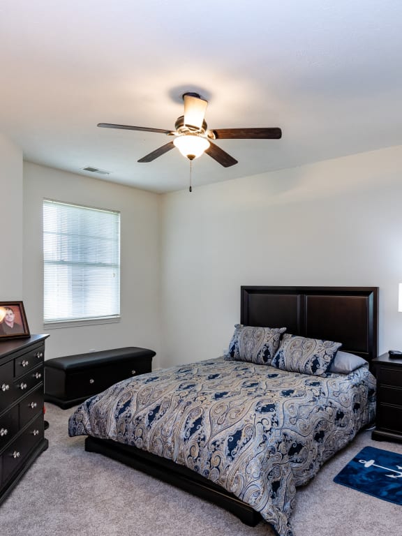 a bedroom with a bed and dressers and a ceiling fan