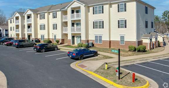 Apartment complex with a parking lot in front.
