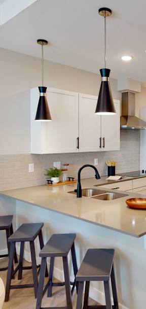A kitchen with a white counter top and stools.