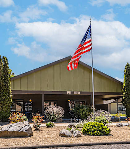 A building with a flag on top and a parking lot in front.