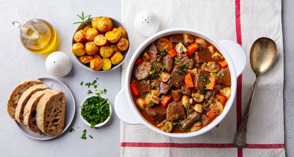 a bowl of beef stew with potatoes and bread