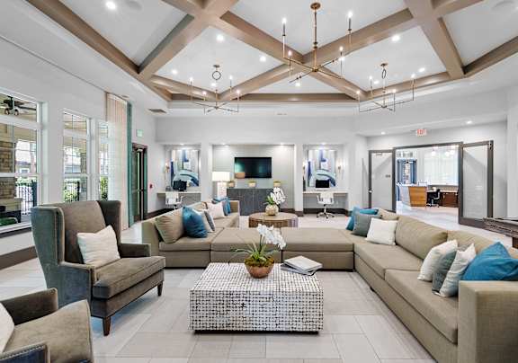 A modern living room with a white sofa, a glass coffee table, and a TV mounted on the wall.